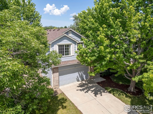1667 Reliance Cir, Superior, CO 80027 - obstructed view of property featuring concrete driveway, a garage, a shingled roof, and brick siding