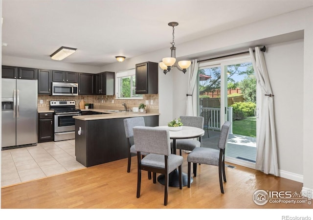 1667 Reliance Cir, Superior, CO 80027 - kitchen with appliances with stainless steel finishes, tasteful backsplash, a peninsula, and light countertops