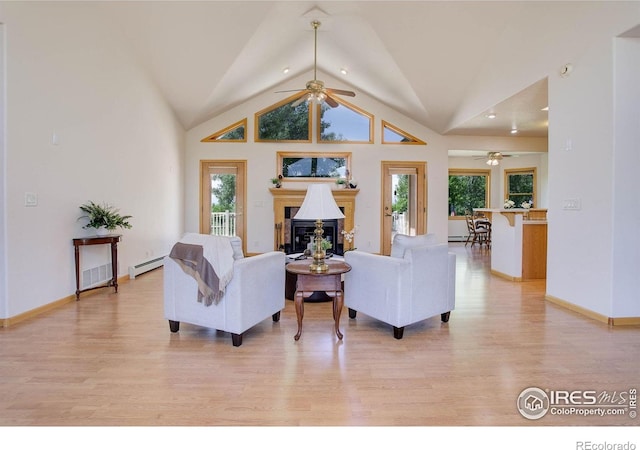 8943 Gander Valley Ln, Windsor, CO 80550 - living area with ceiling fan, baseboard heating, light wood-type flooring, a glass covered fireplace, and vaulted ceiling