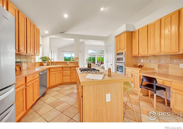 2226 Eagles Nest Dr, Lafayette, CO 80026 - kitchen with stainless steel appliances, backsplash, a breakfast bar, a center island, and light tile patterned floors