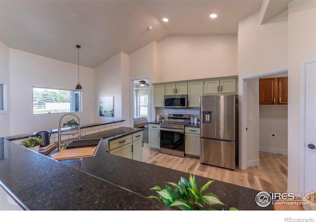 5217 Dry Creek Rd, Evans, CO 80634 - kitchen with stainless steel appliances, high vaulted ceiling, dark countertops, light wood-type flooring, and decorative backsplash