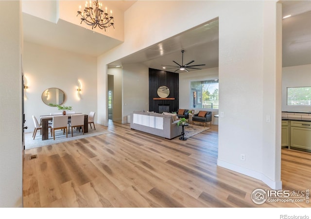 5217 Dry Creek Rd, Evans, CO 80634 - living room with light wood-type flooring, a large fireplace, a chandelier, ceiling fan, and a towering ceiling