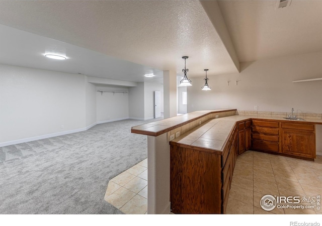 5217 Dry Creek Rd, Evans, CO 80634 - kitchen with tile countertops, light carpet, light tile patterned floors, a peninsula, and pendant lighting