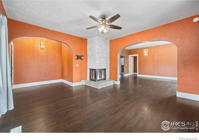 556 Lincoln Ave, Nunn, CO 80648 - unfurnished living room featuring arched walkways, a textured wall, wood finished floors, a ceiling fan, and a stone fireplace