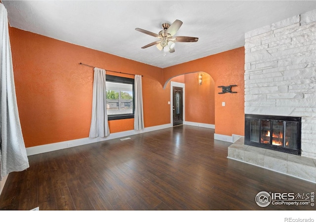 556 Lincoln Ave, Nunn, CO 80648 - unfurnished living room featuring a ceiling fan, arched walkways, wood finished floors, and a fireplace