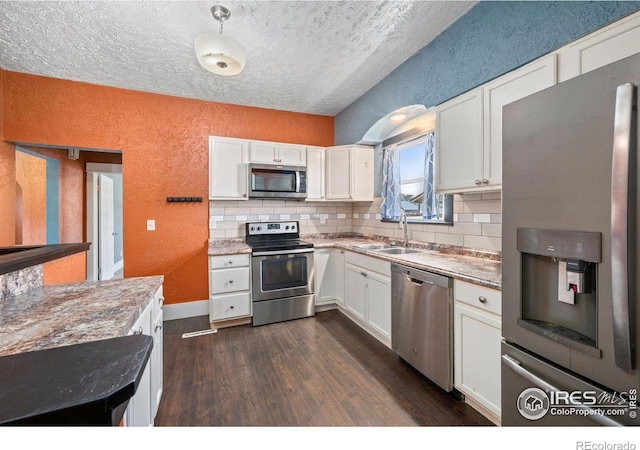 556 Lincoln Ave, Nunn, CO 80648 - kitchen with stainless steel appliances, a textured wall, dark wood-type flooring, backsplash, and white cabinetry