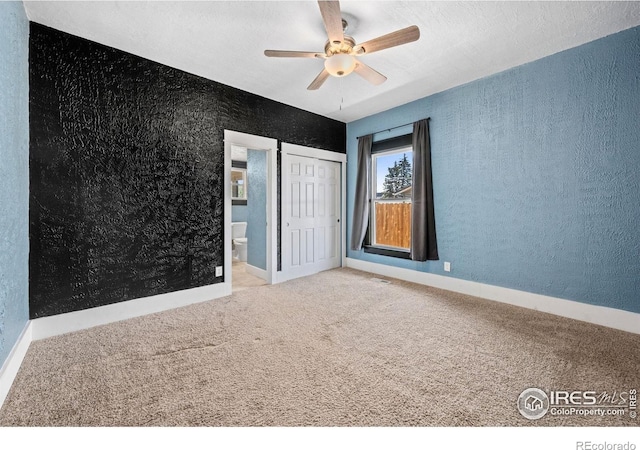 556 Lincoln Ave, Nunn, CO 80648 - unfurnished bedroom featuring carpet, a textured wall, a closet, connected bathroom, and a ceiling fan