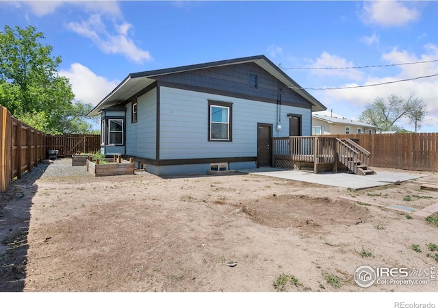 556 Lincoln Ave, Nunn, CO 80648 - rear view of property with a fenced backyard, a wooden deck, and a garden