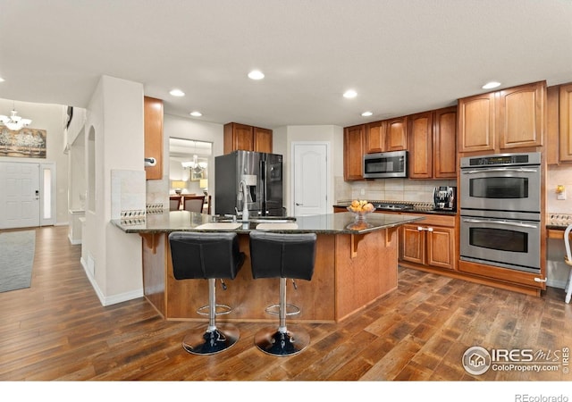 8383 Castaway Dr, Windsor, CO 80528 - kitchen with stainless steel appliances, a chandelier, dark wood-style floors, a breakfast bar, and recessed lighting