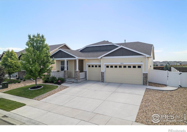 973 Mt Andrew Dr, Severance, CO 80550 - craftsman house with a garage, a gate, stone siding, covered porch, and concrete driveway