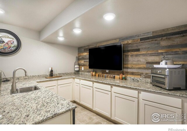973 Mt Andrew Dr, Severance, CO 80550 - kitchen with light stone counters, recessed lighting, wooden walls, and white cabinets