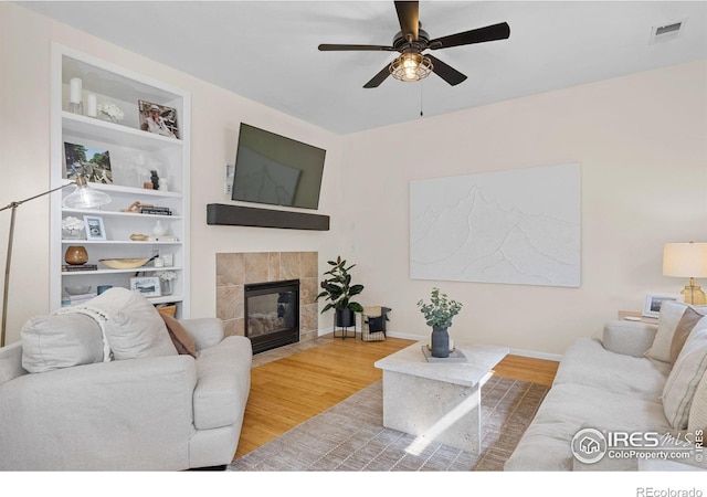 3826 Glenarbor Ln Unit F, Fort Collins, CO 80524 - living area featuring a ceiling fan, wood finished floors, a tiled fireplace, and built in shelves