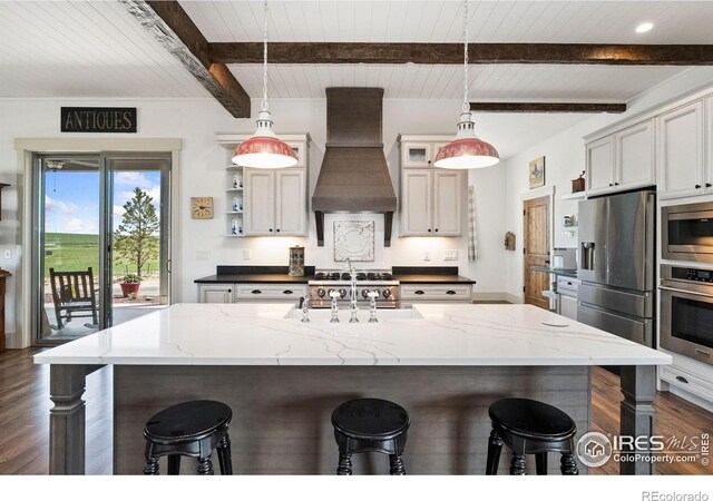 9260 Meadow Farms Dr, Milliken, CO 80543 - kitchen with custom exhaust hood, stainless steel appliances, dark wood-type flooring, a kitchen bar, and a wood ceiling with exposed beams