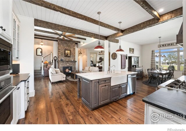 9260 Meadow Farms Dr, Milliken, CO 80543 - kitchen featuring appliances with stainless steel finishes, open floor plan, dark wood finished floors, a fireplace, and ceiling fan