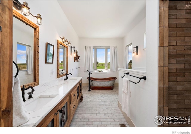 9260 Meadow Farms Dr, Milliken, CO 80543 - full bathroom featuring double vanity, a freestanding bath, and brick patterned floors