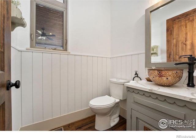 9260 Meadow Farms Dr, Milliken, CO 80543 - half bath with a wainscoted wall, vanity, wood finished floors, and a ceiling fan