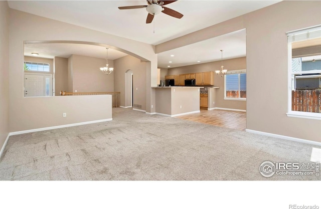 3664 Claycomb Ln, Johnstown, CO 80534 - unfurnished living room with light carpet, arched walkways, a chandelier, a ceiling fan, and recessed lighting