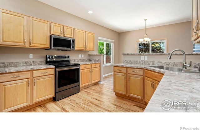 3664 Claycomb Ln, Johnstown, CO 80534 - kitchen featuring appliances with stainless steel finishes, light brown cabinets, light countertops, light wood-style flooring, and a chandelier