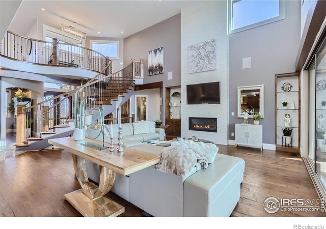 5763 Pelican Shores Dr, Longmont, CO 80504 - living room with a high ceiling, stairs, wood-type flooring, a fireplace, and recessed lighting