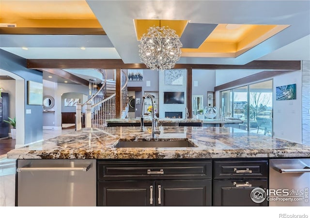5763 Pelican Shores Dr, Longmont, CO 80504 - kitchen featuring arched walkways, open floor plan, a chandelier, stone counters, and dark cabinets