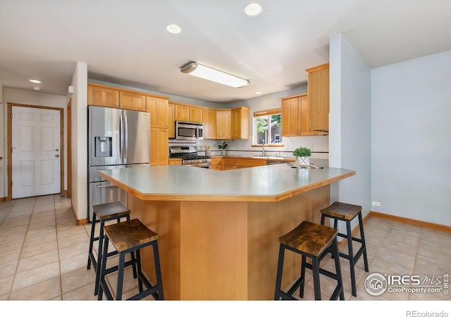 1204 Boulder Ct, Windsor, CO 80550 - kitchen featuring stainless steel appliances, a kitchen breakfast bar, light tile patterned floors, recessed lighting, and light countertops
