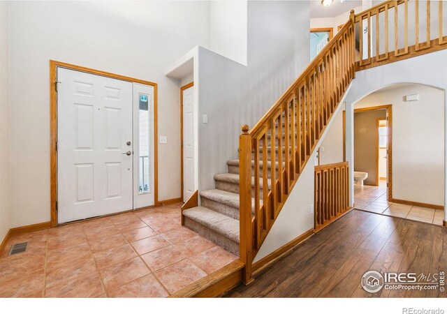 1204 Boulder Ct, Windsor, CO 80550 - entrance foyer featuring arched walkways, a towering ceiling, stairs, and hardwood / wood-style floors