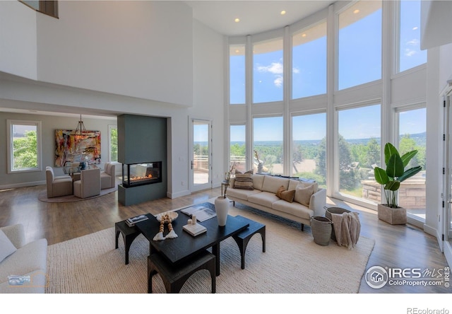 3747 Mountain Laurel Pl, Boulder, CO 80304 - living room featuring a high ceiling, wood finished floors, a glass covered fireplace, and recessed lighting