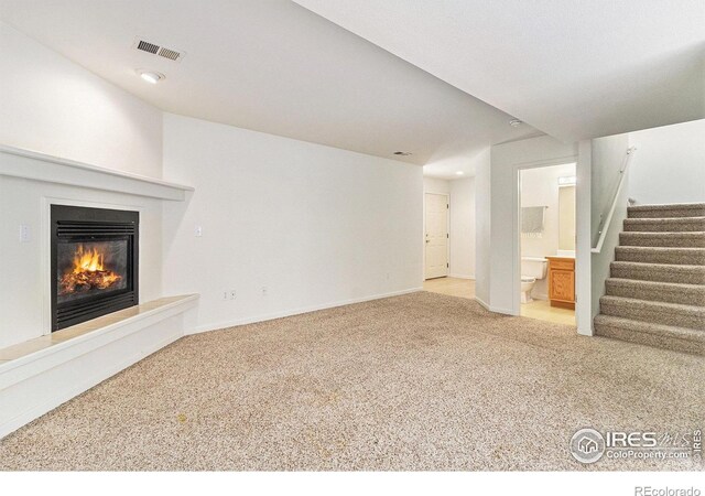 911 Tulip St Unit C, Longmont, CO 80501 - unfurnished living room with light colored carpet, stairs, and a glass covered fireplace