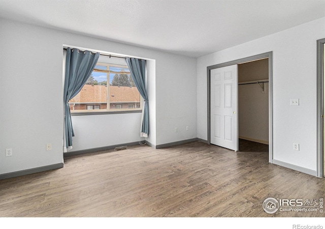 911 Tulip St Unit C, Longmont, CO 80501 - unfurnished bedroom with wood finished floors, a walk in closet, and a closet