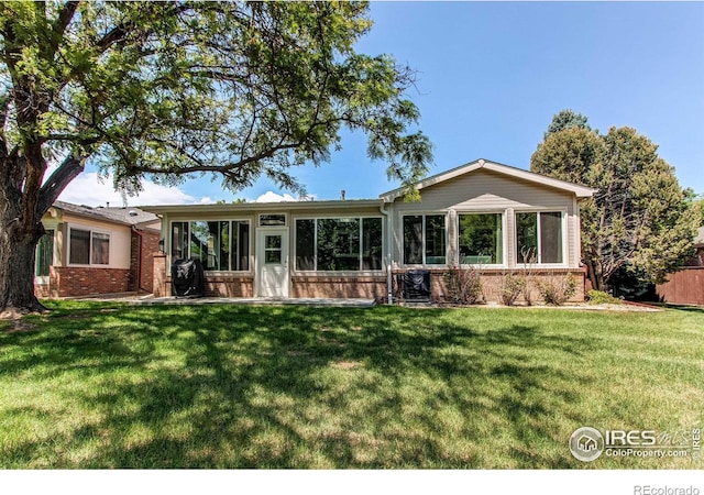 1331 Iva Ct, Fort Collins, CO 80525 - rear view of house with brick siding, a sunroom, and a lawn