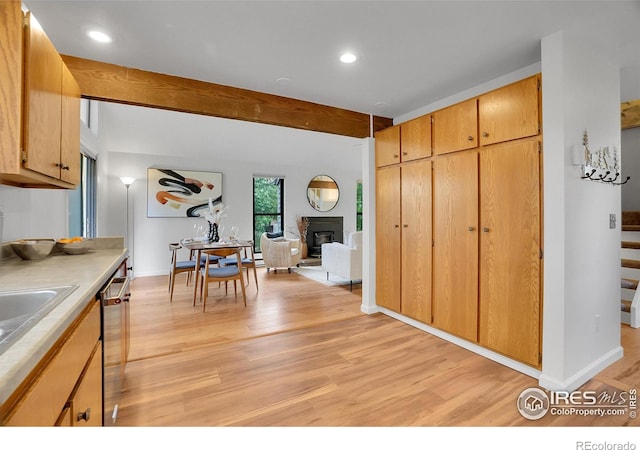 3880 Telluride Pl, Boulder, CO 80305 - kitchen featuring light wood-style flooring, beamed ceiling, a glass covered fireplace, stainless steel dishwasher, and light countertops