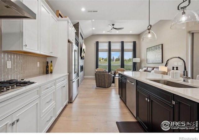 1768 Barefoot Dr, Windsor, CO 80550 - kitchen with range hood, white cabinetry, light wood-type flooring, open floor plan, and decorative light fixtures