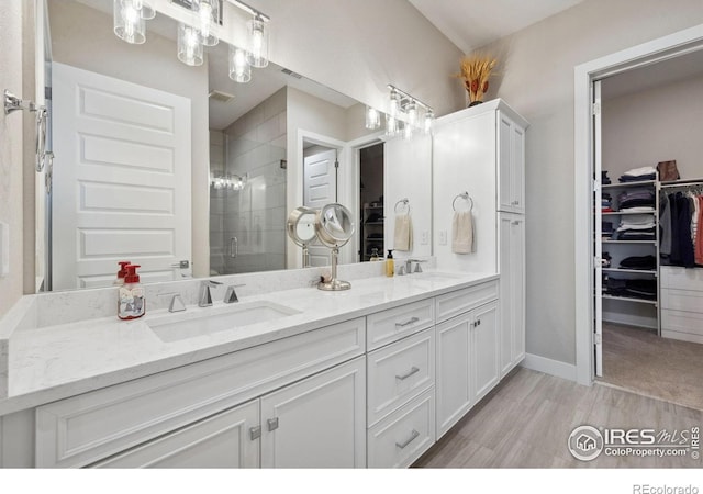 1768 Barefoot Dr, Windsor, CO 80550 - bathroom with double vanity, a shower stall, a walk in closet, and wood finished floors