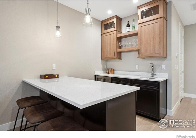 1768 Barefoot Dr, Windsor, CO 80550 - kitchen with open shelves, a kitchen bar, a peninsula, glass insert cabinets, and light wood-style floors