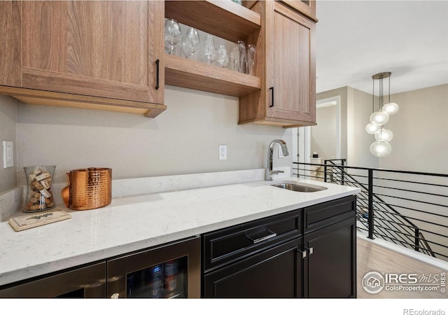 1768 Barefoot Dr, Windsor, CO 80550 - kitchen featuring light wood-style flooring, decorative light fixtures, light stone counters, open shelves, and dark cabinets