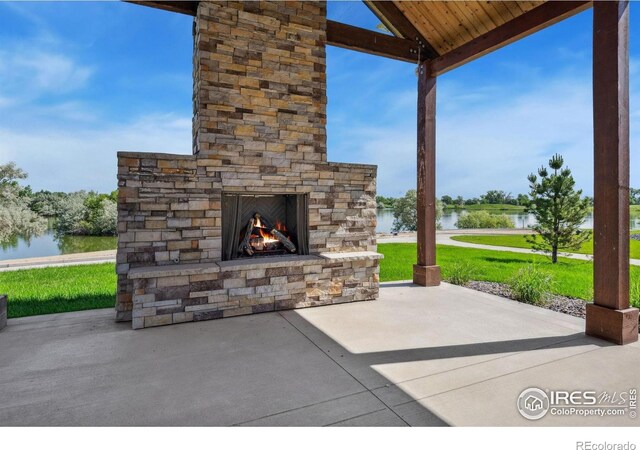 1768 Barefoot Dr, Windsor, CO 80550 - view of patio with an outdoor stone fireplace and a water view