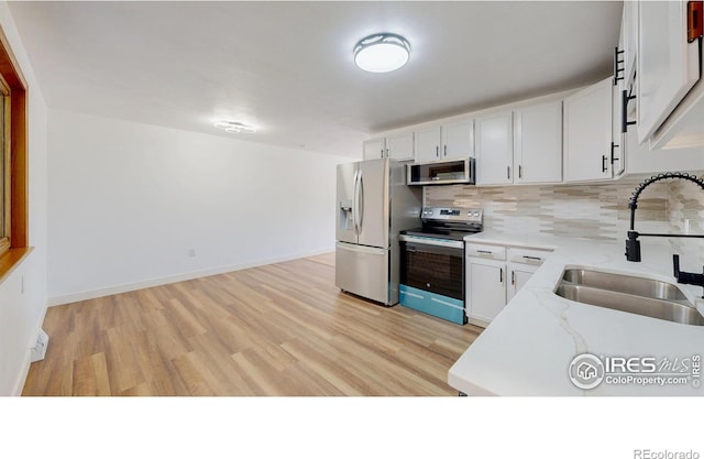 235 N 12th Ave, Brighton, CO 80601 - kitchen with stainless steel appliances, backsplash, light wood finished floors, white cabinetry, and light stone countertops
