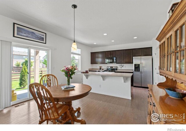6792 Covenant Ct, Timnath, CO 80547 - kitchen with appliances with stainless steel finishes, light wood-type flooring, dark brown cabinetry, recessed lighting, and light countertops
