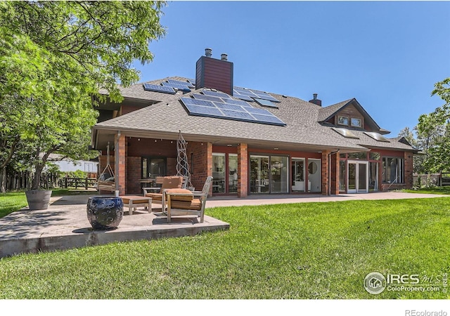 7975 Anchor Dr, Longmont, CO 80504 - rear view of property with a patio, a lawn, solar panels, brick siding, and a chimney