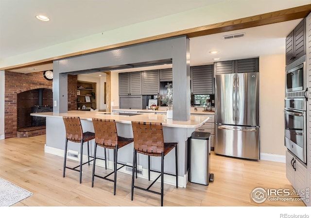 7975 Anchor Dr, Longmont, CO 80504 - kitchen with stainless steel appliances, light countertops, a breakfast bar, light wood-type flooring, and recessed lighting