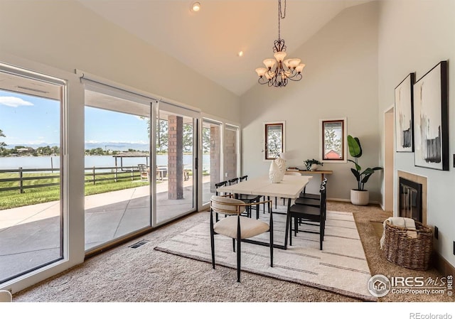 7975 Anchor Dr, Longmont, CO 80504 - carpeted dining space with a water view, a chandelier, high vaulted ceiling, and a tile fireplace