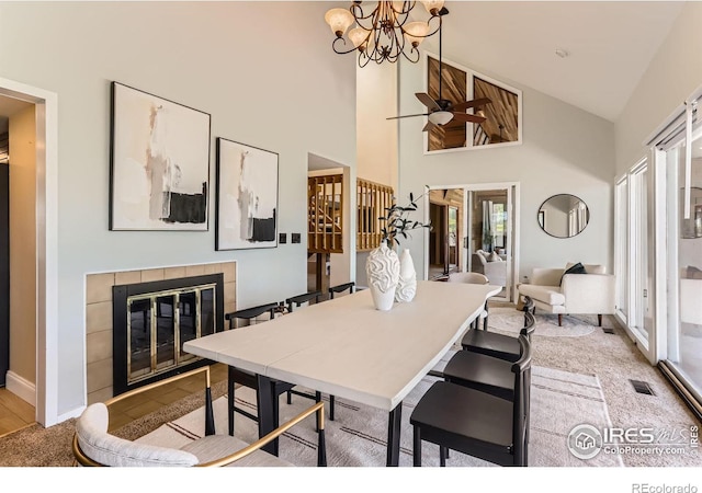 7975 Anchor Dr, Longmont, CO 80504 - carpeted dining space featuring a tiled fireplace, high vaulted ceiling, and a chandelier
