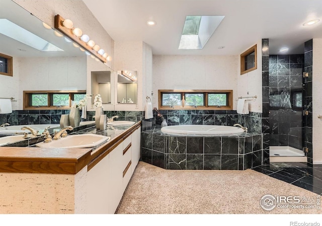 7975 Anchor Dr, Longmont, CO 80504 - bathroom featuring a skylight, a bath, double vanity, a stall shower, and recessed lighting