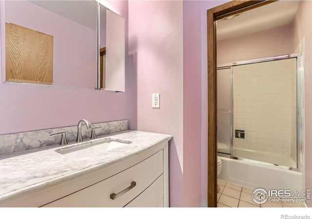7975 Anchor Dr, Longmont, CO 80504 - full bathroom featuring vanity, tile patterned floors, shower / bath combination with glass door, and a textured wall