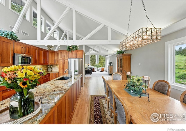 178 Balsam Ln, Boulder, CO 80304 - kitchen featuring appliances with stainless steel finishes, high vaulted ceiling, light wood-style flooring, brown cabinetry, and light stone countertops