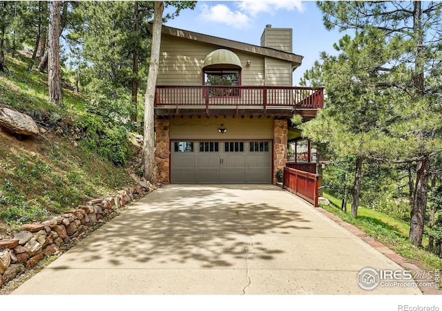 178 Balsam Ln, Boulder, CO 80304 - chalet / cabin with an attached garage, concrete driveway, a chimney, stone siding, and a balcony