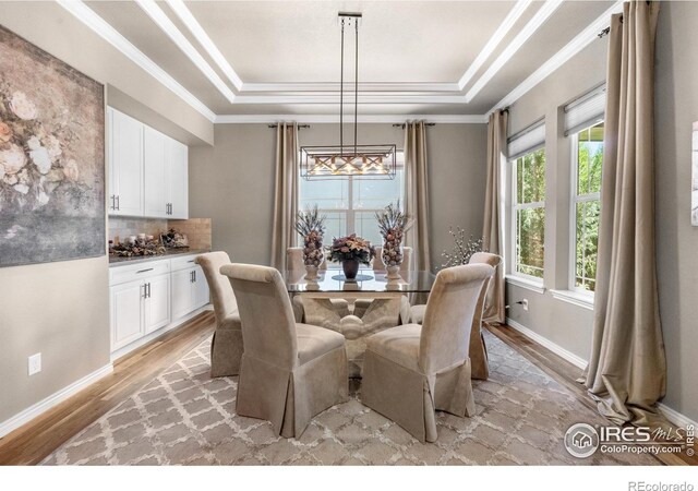 1976 Cayman Dr, Windsor, CO 80550 - dining room featuring a raised ceiling, a chandelier, light wood-style floors, and crown molding