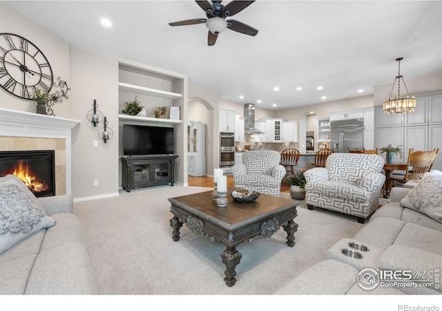1976 Cayman Dr, Windsor, CO 80550 - living area featuring ceiling fan, a tile fireplace, arched walkways, recessed lighting, and light carpet