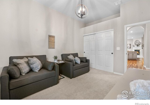 1976 Cayman Dr, Windsor, CO 80550 - living area with carpet flooring, a chandelier, a warm lit fireplace, and arched walkways