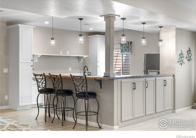 1976 Cayman Dr, Windsor, CO 80550 - kitchen with freestanding refrigerator, white cabinets, open shelves, a kitchen breakfast bar, and recessed lighting